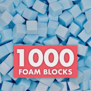May include: A close-up of numerous light blue foam blocks. A red rectangle in the center displays the text "1000 FOAM BLOCKS" in white, bold letters. The blocks are scattered, creating a textured surface.
