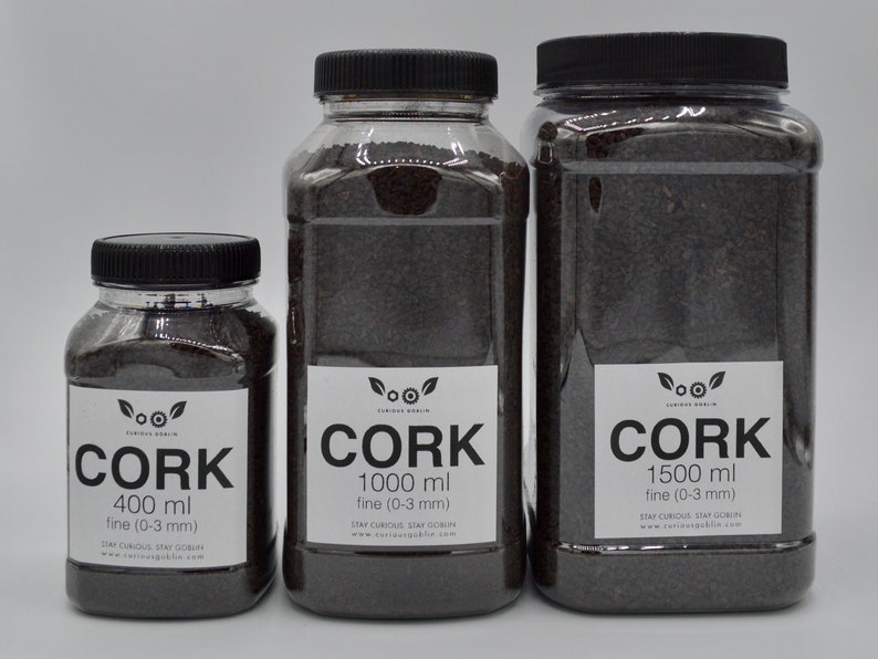 May include: Three clear plastic jars filled with dark brown cork granules. The jars are labeled "Cork" with different sizes: 400 ml, 1000 ml, and 1500 ml. The labels also indicate that the cork is "fine (0-3 mm)".