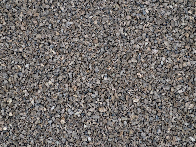 May include: A close-up view of a surface covered in small, gray gravel. The gravel is tightly packed together, creating a uniform texture.