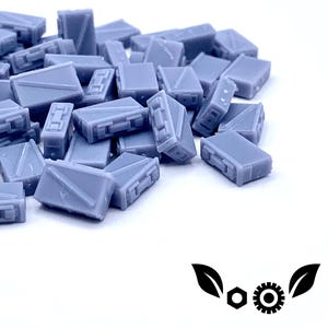 May include: A pile of small, gray, plastic boxes. The boxes are all the same size and shape, and they are arranged in a random order.