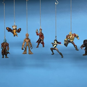 May include: Eight Guardians of the Galaxy characters hanging from chains. The characters are Rocket Raccoon, Groot, Star-Lord, Gamora, Drax the Destroyer, Ronan the Accuser, and Nebula. The characters are all in their signature poses and costumes.