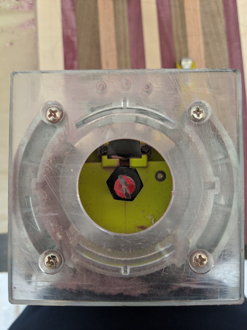 May include: Close-up of a clear plastic base for a router with a black and red screw in the center.