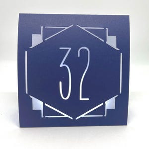 ART DECO Table Number LUMINARIES are made with sturdy card stock and sheer vellum paper. The numbers and modern design are cut out  so your battery tea lights can shine through.The glowing numbers make it easy for guests to find their table.