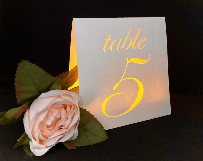 Classic table number luminaries are made with Cream, Gold Leaf,  or Silver Gray Card Stock. This simple design fits with many color themes.