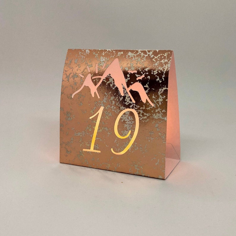 Mountain Table Numbers are made from Copper Mercury Glass or white card stock. These Wedding Luminaries set the rustic western mood. You add a tea light and the romantic glow begins!