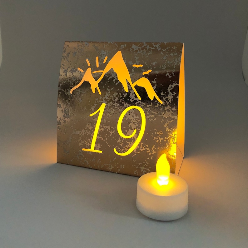 Mountain Table Numbers are made from Copper Mercury Glass or white card stock. These Wedding Luminaries set the rustic western mood. You add a tea light and the romantic glow begins!