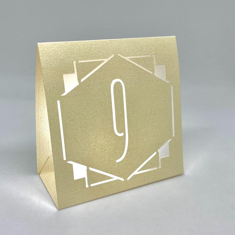 ART DECO Table Number LUMINARIES are made with sturdy card stock and sheer vellum paper. The numbers and modern design are cut out  so your battery tea lights can shine through.The glowing numbers make it easy for guests to find their table.