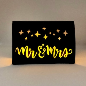 Star Design Night Table Number LUMINARIES are made with black card stock and sheer vellum paper. The Mr & Mrs design is cut out for use with LED tea lights can shine through (not included.) Available for free with a set of 1-10 Star Table Numbers.