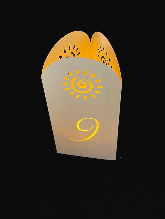 SUNNY TOWER Table Number Luminaries are 3-sided cutout arches. Colors include kraft, cream, blush, or light purple.