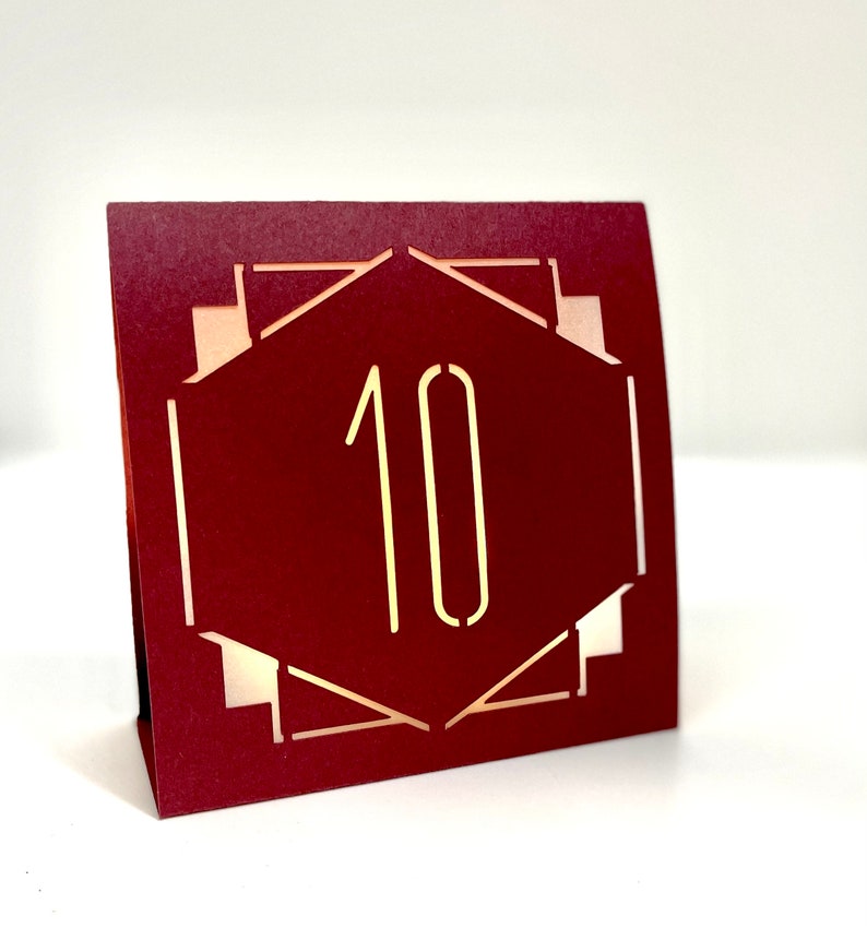 ART DECO Table Number LUMINARIES in are made with sturdy card stock and sheer vellum paper. The numbers and modern design are cut out  so your battery tea lights can shine through.The glowing numbers make it easy for guests to find their table.