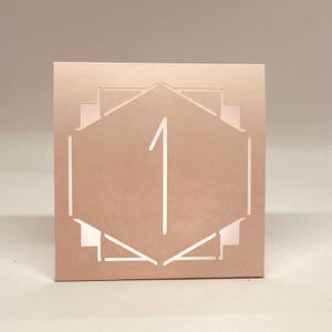 ART DECO Table Number LUMINARIES are made with sturdy card stock and sheer vellum paper. The numbers and modern design are cut out  so your battery tea lights can shine through.The glowing numbers make it easy for guests to find their table.