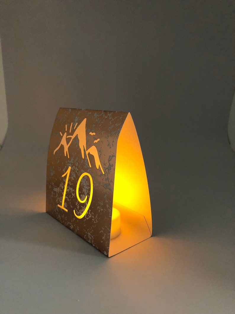 Mountain Table Numbers are made from Copper Mercury Glass or white card stock. These Wedding Luminaries set the rustic western mood. You add a tea light and the romantic glow begins!