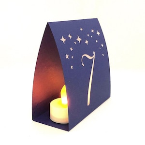 Star Design Night Table Number LUMINARIES are made with navy card stock and sheer vellum paper. The number and design is cut out for use with LED tea lights can shine through (not included.) The glowing numbers make it easy for guests to find their table.