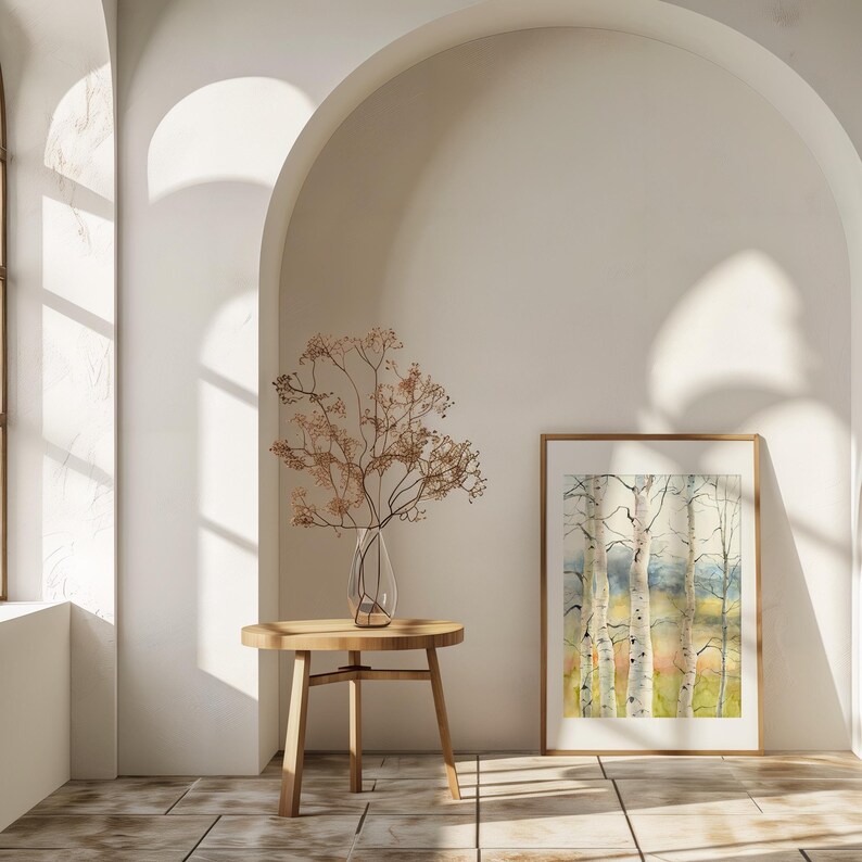 May include: A watercolor painting of birch trees in a wooden frame, displayed in a bright room. A small wooden table holds a clear glass vase with dried branches. The room has arched doorways and a window.