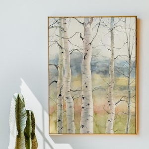 May include: Watercolor painting of birch trees in a gold frame. The trees have white bark with black markings and are set against a backdrop of soft greens, yellows, and blues. The artwork is displayed on a white wall.