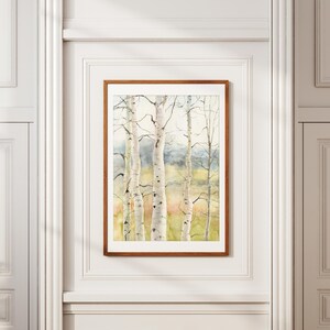May include: A framed watercolor painting of birch trees with white bark and delicate branches. The artwork features a soft color palette of greens, yellows, and blues, creating a serene forest scene. The frame is a warm brown.