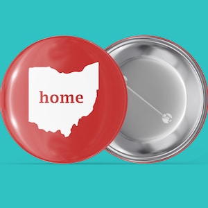 May include: A red button with a white outline of the state of Ohio and the word "home" inside. The back of the button is silver.