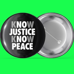 May include: A black button with a white inscription that reads "KNOW JUSTICE KNOW PEACE". The back of the button is silver.
