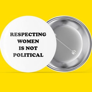 May include: White button with black text that reads "Respecting Women Is Not Political". The back of the button is silver.