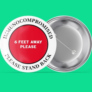 May include: White button with a red circle in the centre. The text on the button reads "Immunocompromised 6 feet away please please stand back".