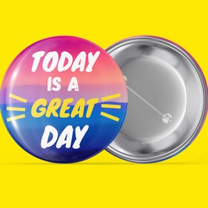 May include: A round button with a colourful sunset background and the text "TODAY IS A GREAT DAY" in white and yellow lettering.