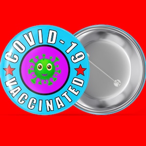 Könnte beinhalten: Ein blauer Knopf mit weißem Rand und dem Text "COVID-19 VACCINATED" in Weiß. Auf jeder Seite des Textes befindet sich ein roter Stern. In der Mitte des Knopfes befindet sich ein grünes Cartoon-Virus mit einem lächelnden Gesicht.