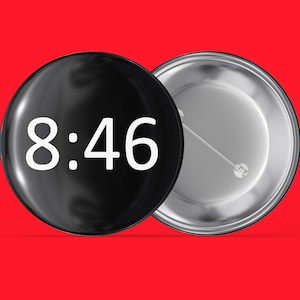 May include: A black button with a white background and the text "8:46" printed on it. The button is attached to a silver backing.