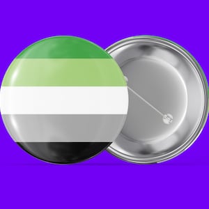 May include: A green, light green, white, gray, and black striped button with a silver back. The button has a pin on the back.