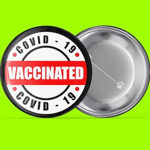 Könnte beinhalten: Ein schwarz-weißer Knopf mit einem roten Band, auf dem "COVID-19 GEIMPFT COVID-19" steht. Die Rückseite des Knopfes ist silber.