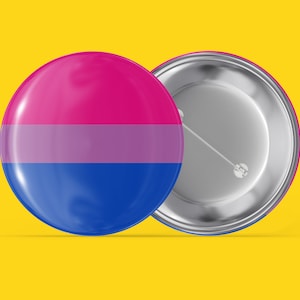 Op de afbeelding: Een ronde knop met een gestreept ontwerp in roze, lavendel en blauw. De knop is bevestigd aan een zilveren metalen achterkant met een pin.