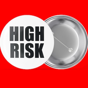 May include: A white button with a black background and the text "HIGH RISK" printed in black.