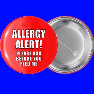 Könnte beinhalten: Roter Knopf mit weißem Text, der "Allergie-Warnung! Bitte fragen Sie, bevor Sie mich füttern." lautet.