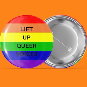 Op de afbeelding: Een regenboogkleurige knop met de tekst "LIFT UP QUEER VOICES" in zwart.