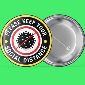 Könnte beinhalten: Ein schwarzer und gelber Knopf mit dem Text "Bitte halten Sie Abstand" und einem roten Kreis mit einer schwarzen stilisierten Coronavirus-Grafik mit einer diagonalen roten Linie.