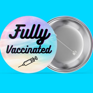 Könnte beinhalten: Ein runder Knopf mit einem bunten Hintergrund und dem Text "Fully Vaccinated" in Schwarz. Unter dem Text befindet sich eine kleine Schwarzweißillustration einer Spritze. Die Rückseite des Knopfes ist silberfarben.