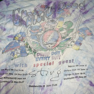 以下が含まれることがあります： タイダイ染めのTシャツに、グレイトフル・デッドのグラフィックと「Dead Day Every Day」の文字、そして「special guest Sting」の文字がプリントされています。Tシャツには、5月と6月のバンドのツアーの日程が記載されています。