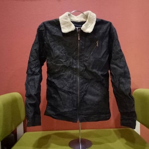 May include: A black denim jacket with a faux fur collar. The jacket has a zipper closure and two pockets.