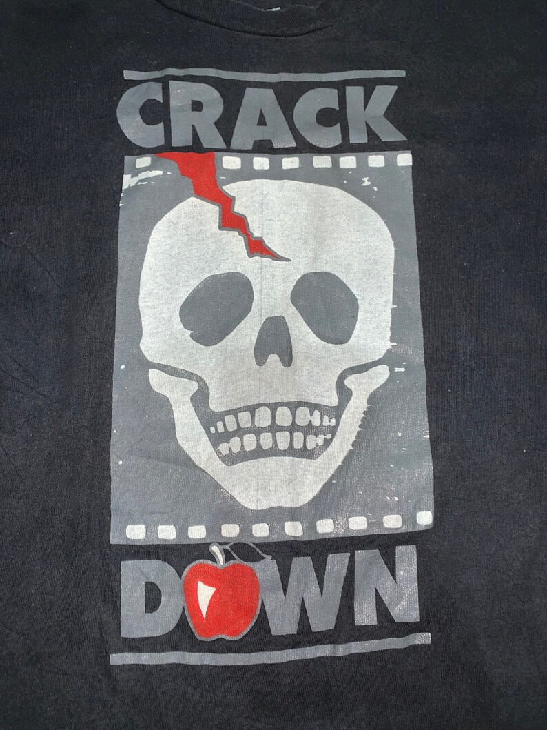 May include: Black t-shirt with a graphic print of a cracked skull with a red crack and the words "CRACK DOWN" with a red apple.