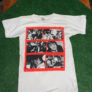 May include: White t-shirt with a red graphic print of a comic book style illustration. The text on the graphic reads "Being the adventures of a young man... who loved a bit of the old ultra-violence. went to jail, was brainwashed...and came out cured...or was he?"
