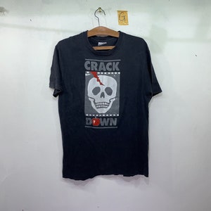 May include: Black t-shirt with a white skull graphic and the text "CRACK DOWN" printed on the front.