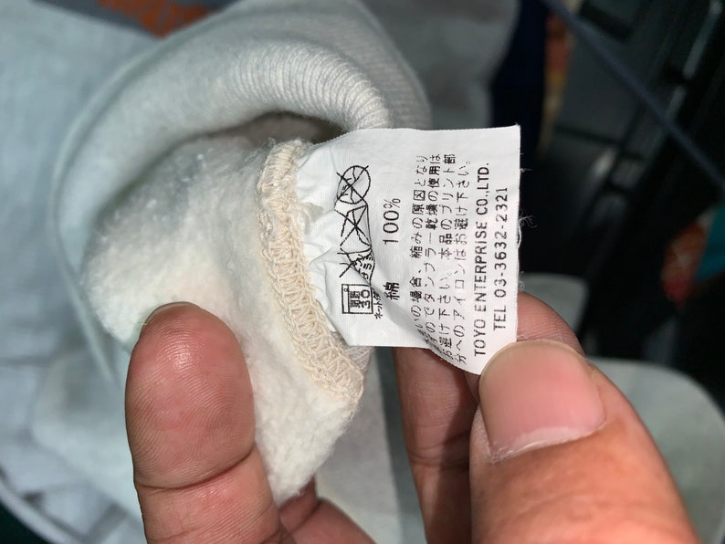 May include: White cotton sweatshirt with a label that reads "100% Cotton" and "TOYO ENTERPRISE CO.,LTD. TEL 03-3632-2321".