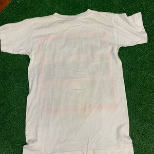 May include: White short-sleeved t-shirt with a red, white, and blue graphic print. The graphic is a square with the words "The Future is Now" inside.
