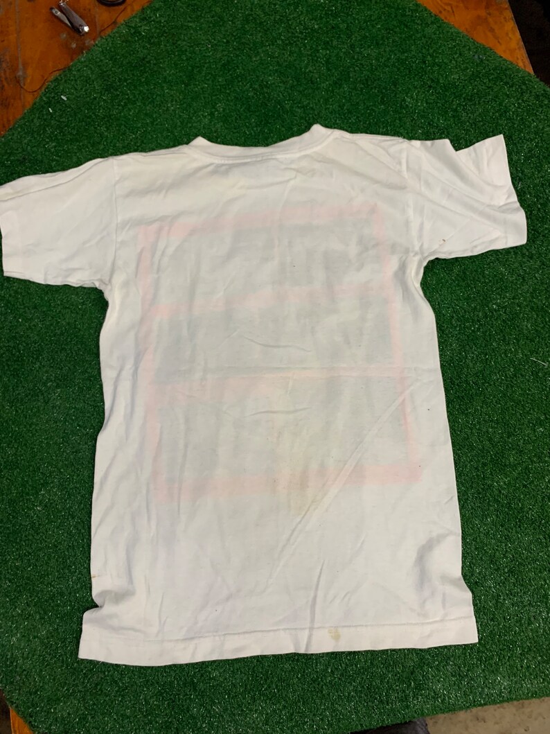 May include: White short-sleeved t-shirt with a red, white, and blue graphic print. The graphic is a square with the words "The Future is Now" inside.