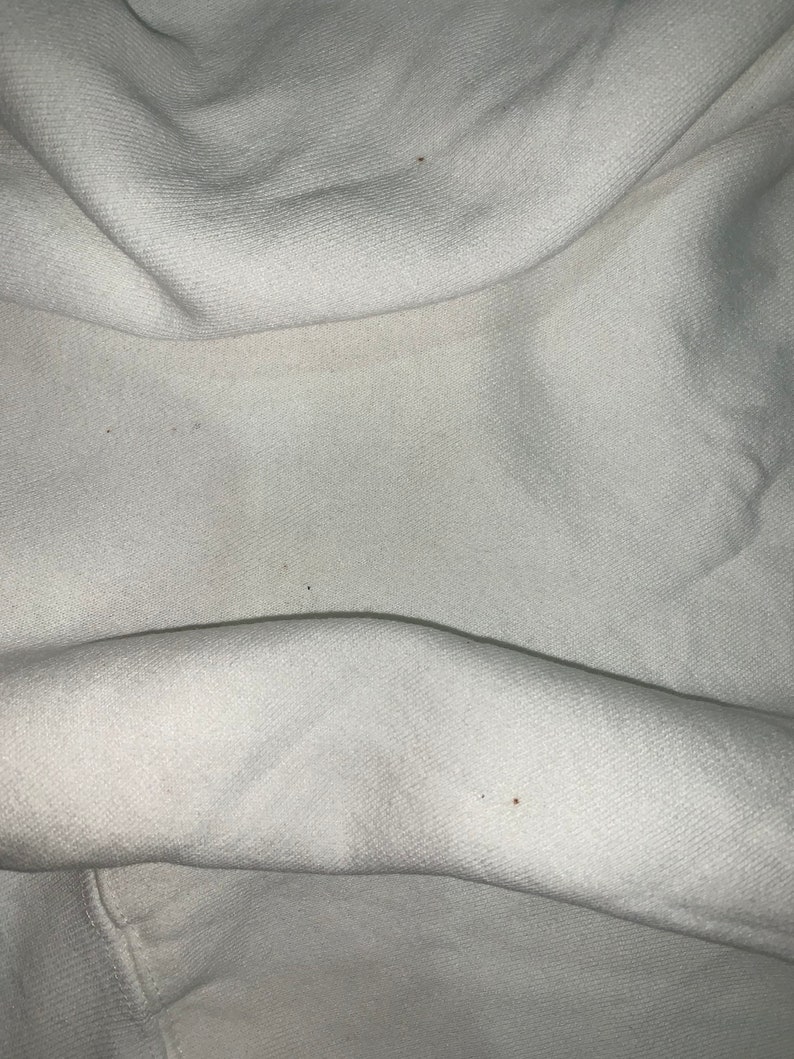 Pu&ograve; includere: Tessuto bianco con alcune piccole macchie marroni.