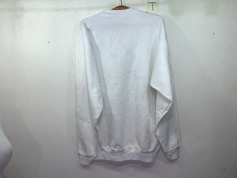 Pu&ograve; includere: Felpa bianca a maniche lunghe con collo rotondo.