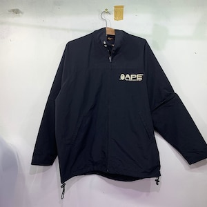 May include: A black zippered jacket with a white "APE" logo on the front. The jacket has a stand-up collar and long sleeves.