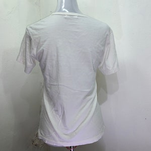 Pu&ograve; includere: Maglietta bianca a maniche corte su un manichino bianco.