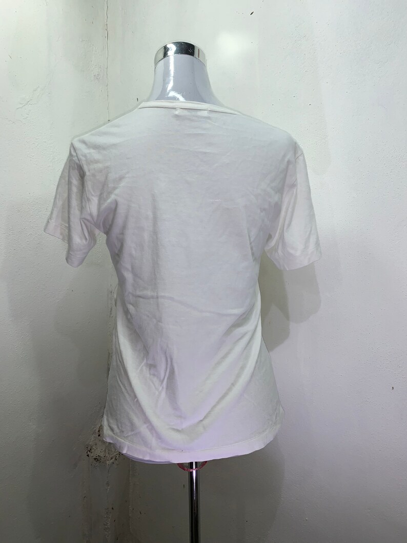 Pu&ograve; includere: Maglietta bianca a maniche corte su un manichino bianco.