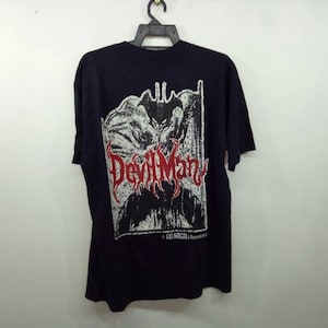 Puede incluir: Camiseta negra con un estampado gráfico blanco y rojo de una banda llamada "DevilMan" con el texto "GO NACALA" debajo.