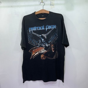 Pode incluir: Camiseta preta com uma estampa gráfica de um pássaro com as asas abertas e o texto "Primal Fear" e "Inner" em uma fonte estilizada.